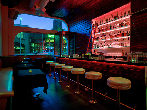 The Powder Room in the evening, with red-lit shelving and the bar.